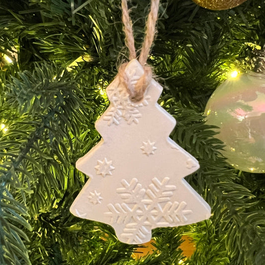 "Handmade air-dry clay tree-shaped ornament with snowflake patterns, featuring a natural twine loop for hanging. Available in customizable holiday scents.