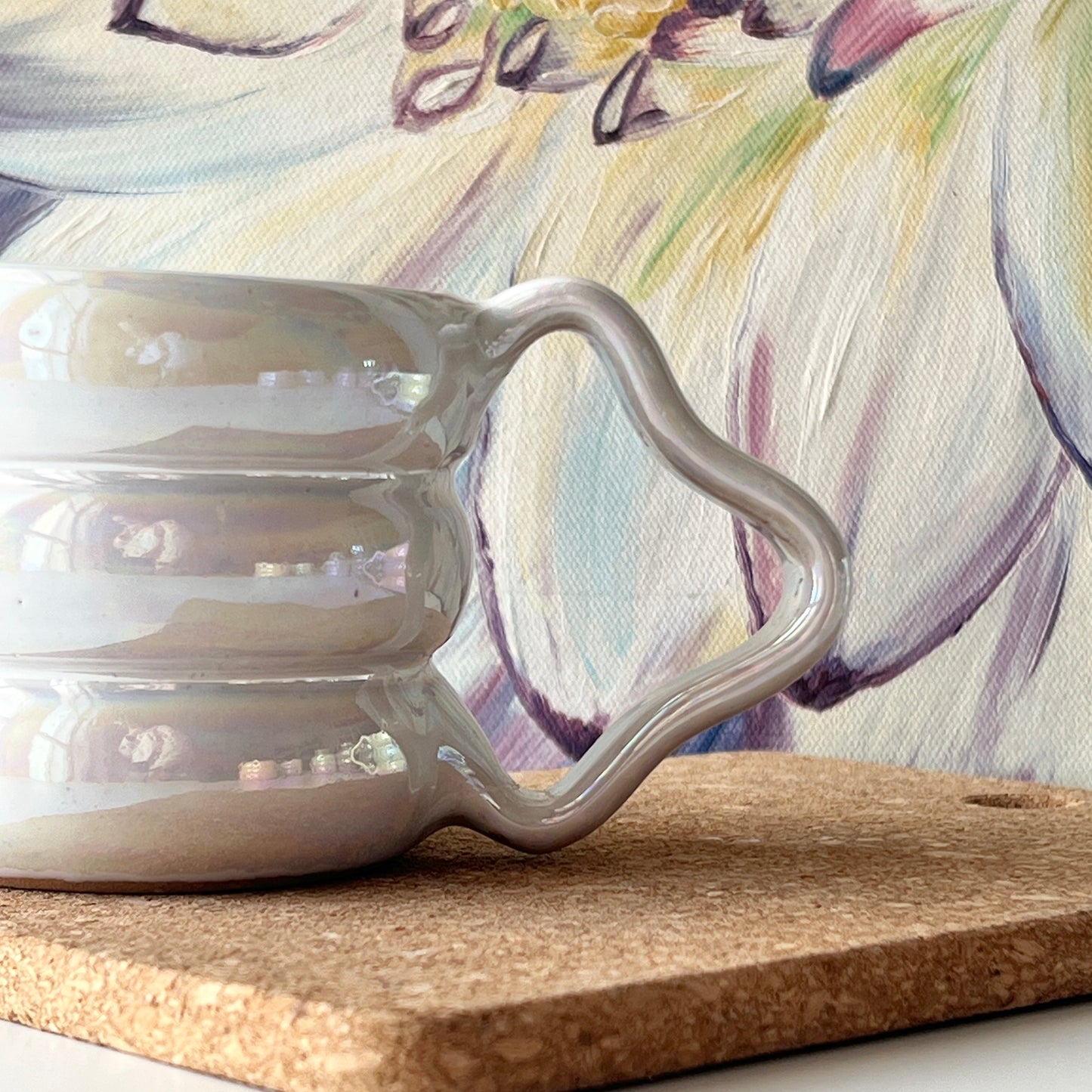 Side view of a handmade ceramic mug with a white iridescent glaze and wavy handle