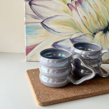 Pair of handmade shimmering purple ceramic mugs with a bubbly design and sculpted handles.